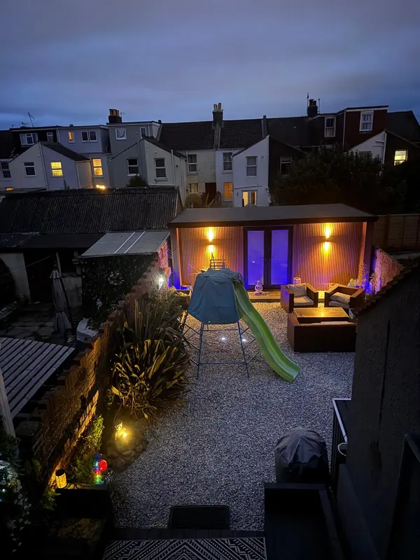 Lit garden room at the end of a landscaped garden in the evening